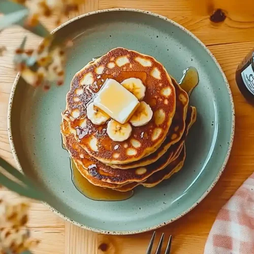 How do you make Kylie Jenner's banana pancakes? 3 Stack of Kylie Jenner's silver-dollar banana pancakes with melting butter and maple syrup on a sage green plate.How Do You Make Kylie Jenner's Banana Pancakes? photo 039